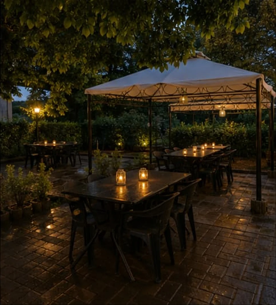Terrasse mit zwei Pavillons und mehreren Tischen, abends beleuchtet